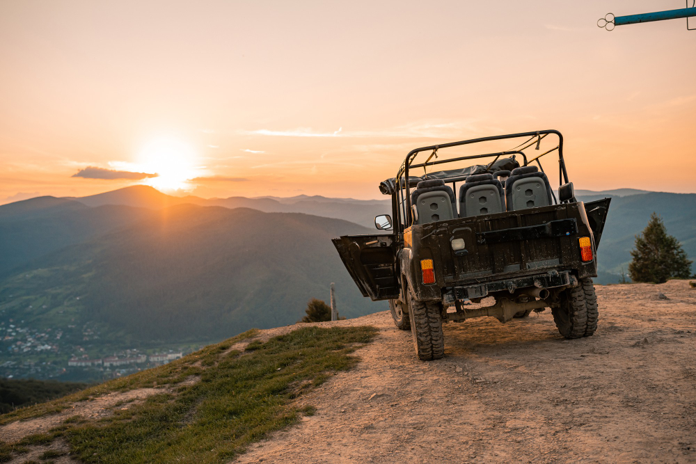 Un todoterreno 4x4 esperando, en la puesta de sol, encima de una montaña con todas sus homologaciones en España.